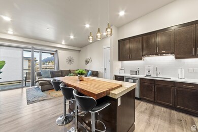 Kitchen with butcher block countertops, a breakfast bar area, dark brown cabinets, open floor plan, and pendant lighting