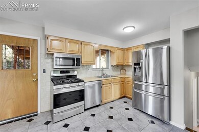 Kitchen with stainless steel appliances, a sink, light brown cabinets, and light countertops