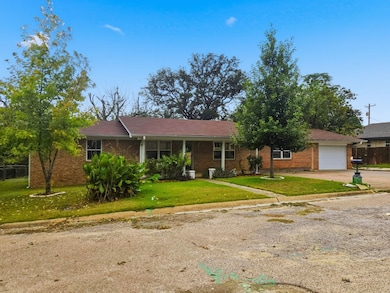 Ranch-style house featuring driveway, brick siding, and a porch