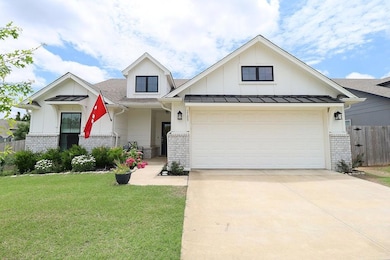 View of front of home with brick siding, concrete driveway, board and batten siding, and roof with shingles
