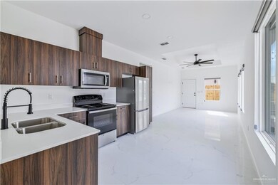 Kitchen featuring appliances with stainless steel finishes, light countertops, light marble finish floors, and ceiling fan