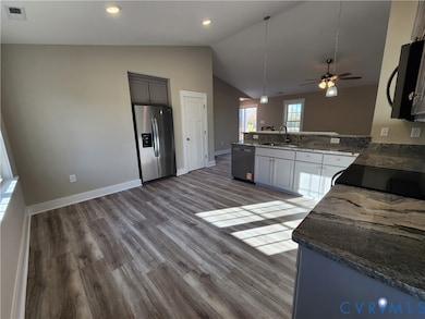 Kitchen featuring black appliances, dark stone countertops, decorative light fixtures, dark wood-style floors, and ceiling fan