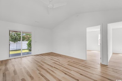 Empty room with vaulted ceiling and light wood fin