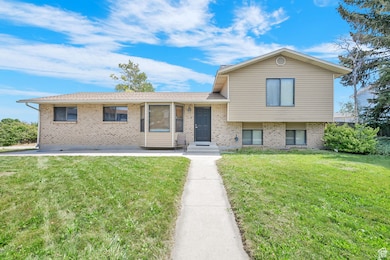 Tri-level home with brick siding and a front yard