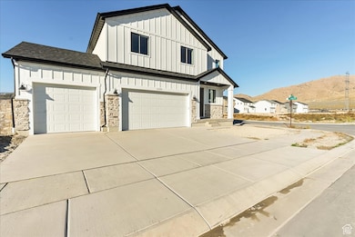 Modern farmhouse style home with board and batten siding, stone siding, concrete driveway, a mountain view, and a shingled roof