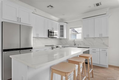 Kitchen with stainless steel appliances, crown molding, a kitchen breakfast bar, a center island, and decorative backsplash