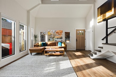 Living room featuring stairs, wood finished floors, and high vaulted ceiling