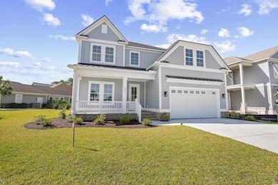 View of front of house with a porch, a garage, driveway, a standing seam roof, and a front yard