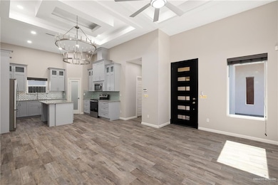 Kitchen featuring gray cabinetry, glass insert cabinets, stainless steel appliances, tasteful backsplash, and a towering ceiling