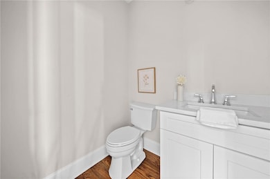 Half bathroom featuring baseboards, toilet, vanity