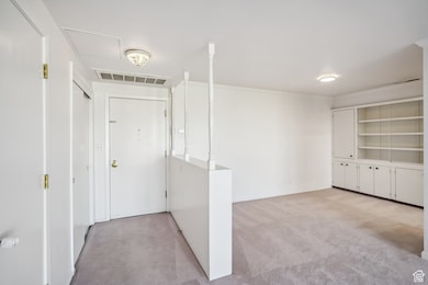 Foyer featuring light colored carpet and ornamental molding