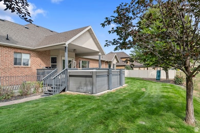 Rear view of property featuring brick siding, a shingled roof, and a hot tub