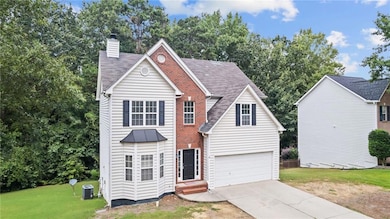 Traditional-style home with a front lawn, a chimney, driveway, a garage, and a shingled roof