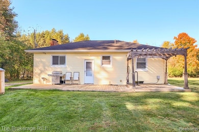 Rear view of property with a yard, a pergola, a chimney, and a wooden deck