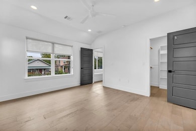Unfurnished bedroom featuring light wood-style floors, a spacious closet, recessed lighting, vaulted ceiling, and a ceiling fan