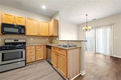 Kitchen with light brown cabinets, a peninsula, st