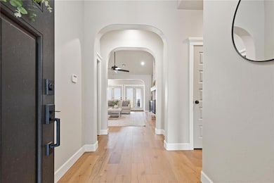 Entrance foyer with arched walkways, light wood-style floors, and a ceiling fan