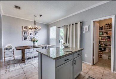 Kitchen featuring a textured wall, gray cabinetry, light stone countertops, ornamental molding, and light tile patterned flooring