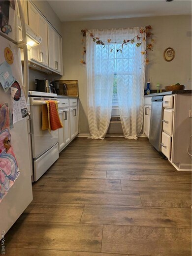 Kitchen featuring refrigerator, dark wood-type flooring, range, dishwasher, and white cabinets