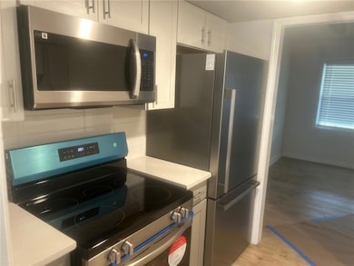 Kitchen featuring white cabinetry, light counterto