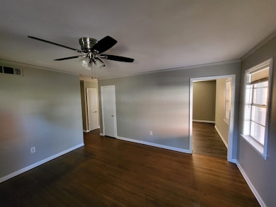 Spare room with ceiling fan, dark wood-type flooring, and ornamental molding