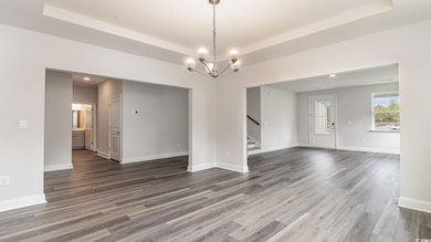 Empty room featuring a tray ceiling, stairway, and