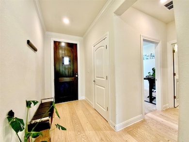 Foyer entrance featuring light wood-style flooring and ornamental molding