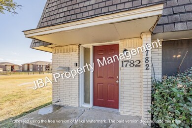Property entrance with brick siding, a shingled roof, mansard roof, and a lawn