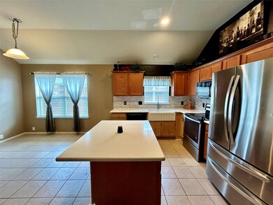 Kitchen featuring black appliances, lofted ceiling, a center island, decorative backsplash, and brown cabinetry