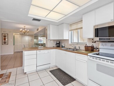 Kitchen with white appliances, a chandelier, a pen