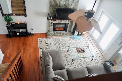 Living room with baseboards, a stone fireplace, wo