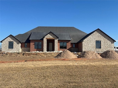 View of front of house featuring stone siding, a standing seam roof, a metal roof, and a front yard