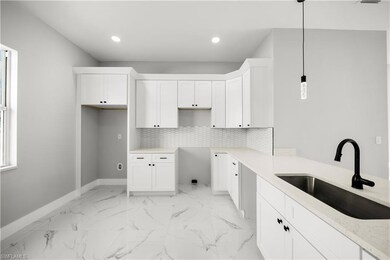 Kitchen featuring white cabinetry, decorative light fixtures, light marble finish flooring, recessed lighting, and tasteful backsplash