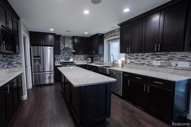 Kitchen with stainless steel appliances, wall chimney range hood, tasteful backsplash, light stone countertops, and recessed lighting