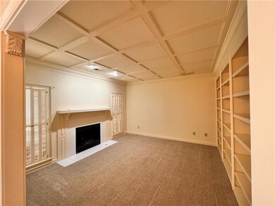 Unfurnished living room featuring crown molding, carpet, a fireplace with flush hearth, and coffered ceiling