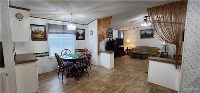 Dining space featuring hardwood / wood-style flooring, ceiling fan with notable chandelier, crown molding, and a textured ceiling