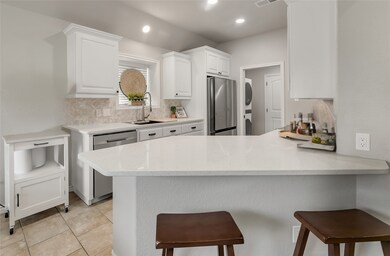 This kitchen features modern white cabinetry, stai