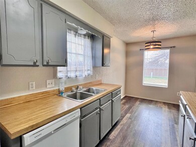 Kitchen with pendant lighting, gray cabinetry, dark hardwood / wood-style floors, and dishwasher