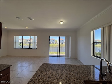 Family room area with light tile patterned floors, a water view, and ornamental molding