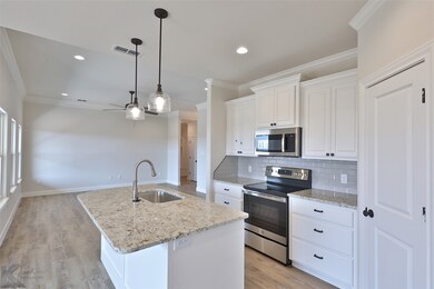 Kitchen with stainless steel appliances, ornamental molding, ceiling fan, backsplash, and white cabinets