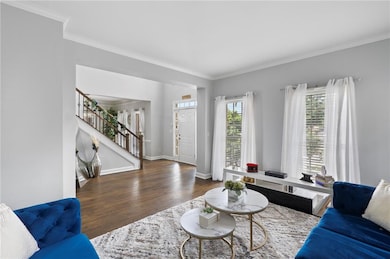 Living room featuring crown molding, dark wood-type flooring, and stairway