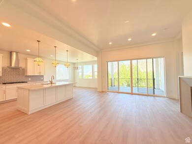 Kitchen featuring a chandelier, a center island with sink, light stone counters, hanging light fixtures, and tasteful backsplash