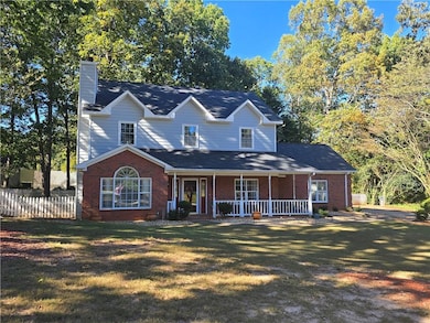 View of front of house featuring a porch, a chimney, and brick siding