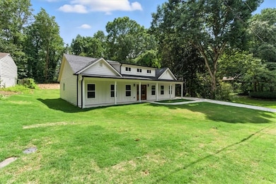 View of front of home with board and batten siding, a porch, a front lawn, and view of scattered trees