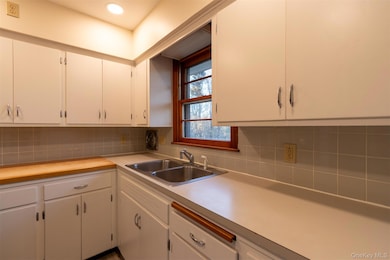 Kitchen with light countertops, tasteful backsplash, and white cabinetry