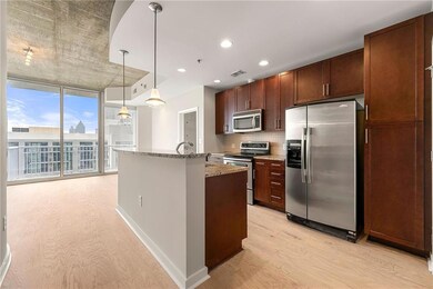 Kitchen featuring appliances with stainless steel finishes, light wood-style floors, floor to ceiling windows, tasteful backsplash, and light stone countertops