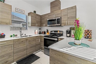 Kitchen with light tile patterned floors, stainless steel appliances, and sink