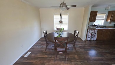 Dining room with crown molding, dark wood-style flooring, and ceiling fan