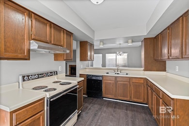Kitchen with white range with electric stovetop, light countertops, a chandelier, dark wood-style floors, and brown cabinets