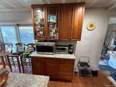 Kitchen with glass insert cabinets, light wood-style flooring, and brown cabinetry